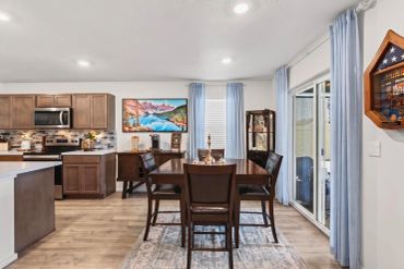 Modern dining area with wooden chairs and kitchen in background.