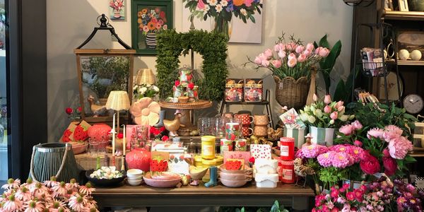 Flower shop display with pink tulips, green plants, and decorative items.