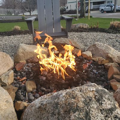 Outdoor fire next to a chair in Maine. 