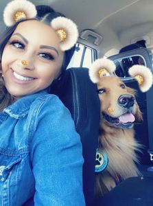 A woman having a selfie with a dog in the car