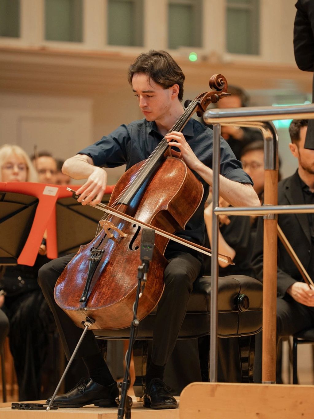 A man passionately playing the cello in an orchestra.