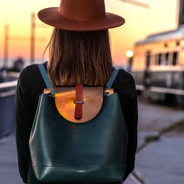Lifestyle photo of a woman wearing a leather backpack at sunset, showcasing  premium fashion product