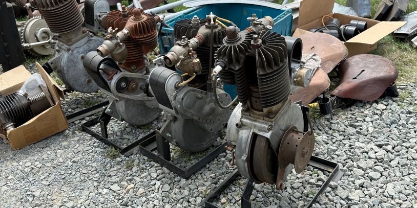 Row of vintage engines displayed on metal stands outdoors.