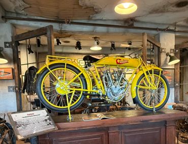 Bright yellow vintage motorcycle displayed on a wooden counter in a rustic setting.