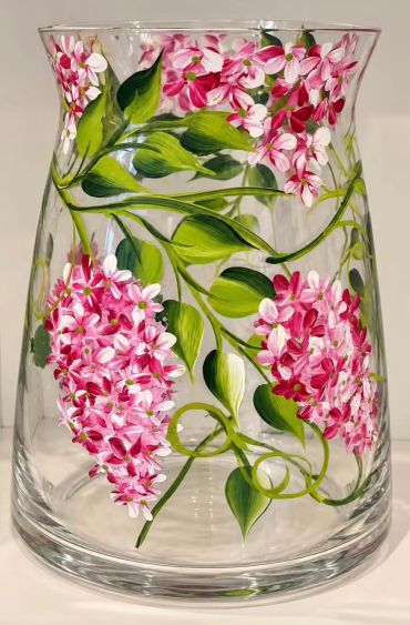 Glass vase with pink floral design and green leaves.