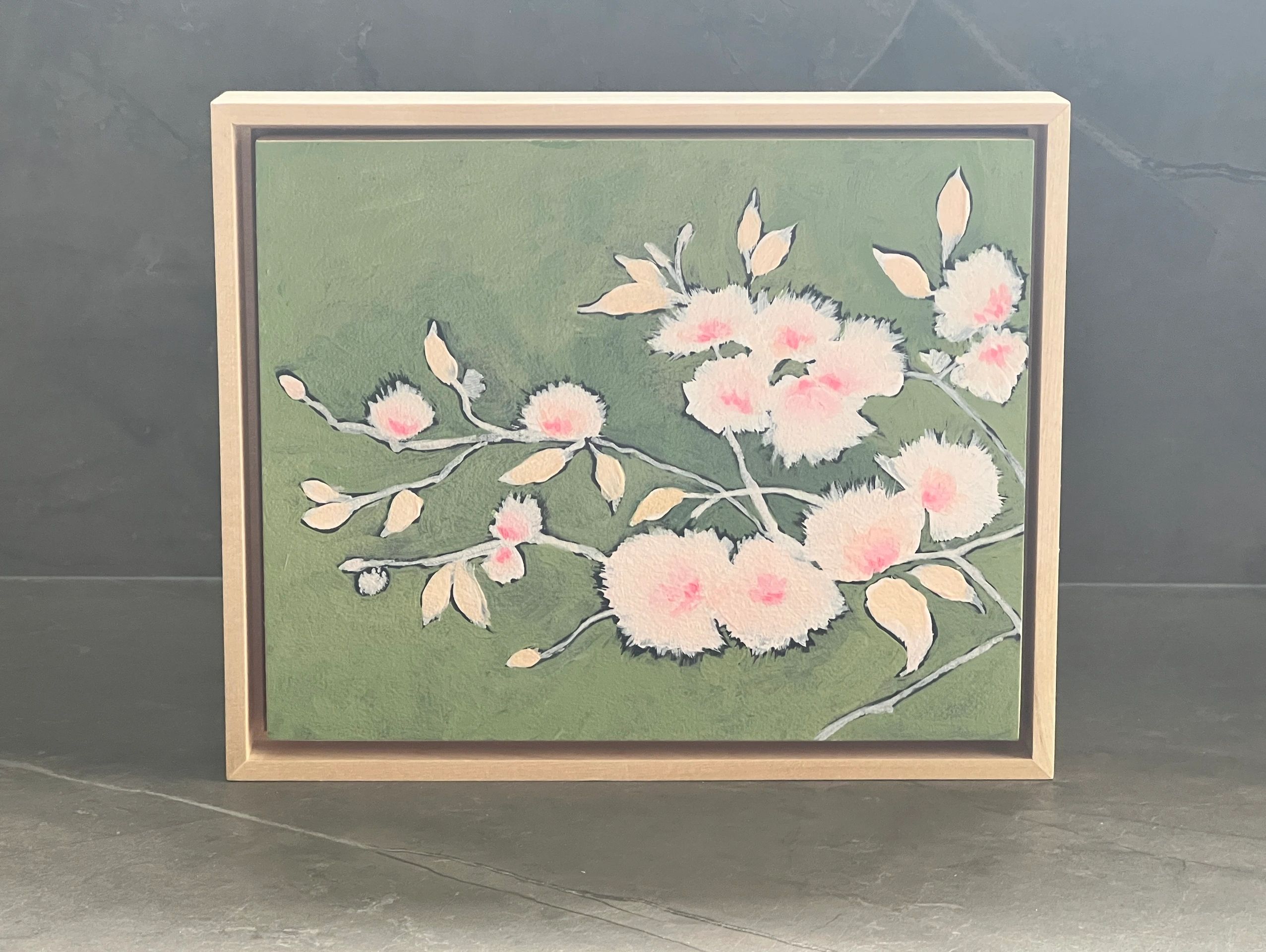Framed painting of soft pink flowers on a green background.
