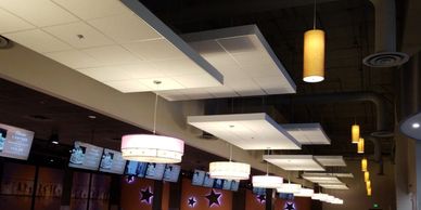 Ceiling with modern light fixtures and TV screens in a sports bar.