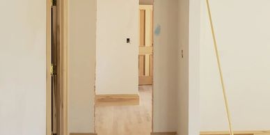 Interior hallway with beige walls and wooden doors under renovation.