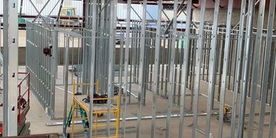Interior construction site with metal framing for walls in progress.