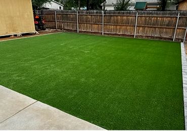A backyard with a neatly installed artificial turf lawn.