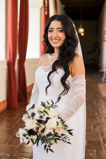 Bride in white dress holding bouquet and smiling.