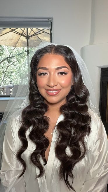 Bride with long wavy hair and veil smiling.