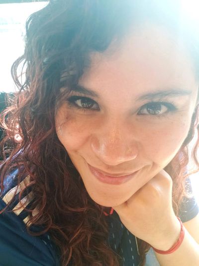 Close-up of a smiling woman with curly hair and bright eyes.