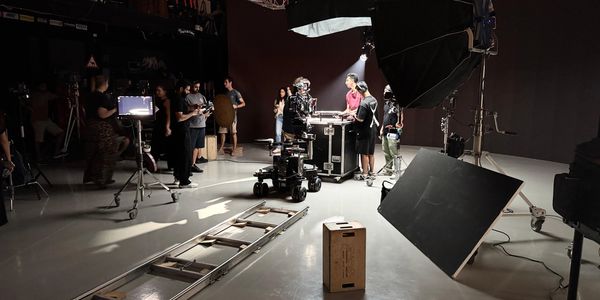 Film crew setting up a scene on a professional studio set with lighting and camera equipment.