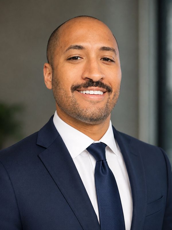 Confident man in a navy suit and tie smiling at the camera.