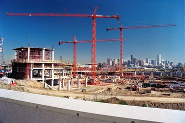 Large construction site with cranes and city skyline in the background.
