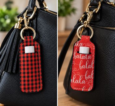 Two red hand sanitizer holders hanging on a black bag.