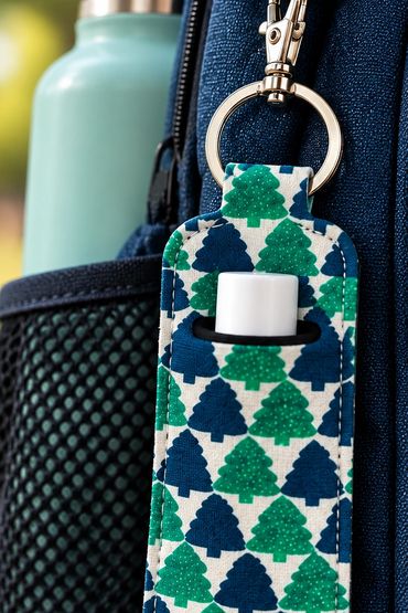 Keychain holder with patterned trees and a small container inside.