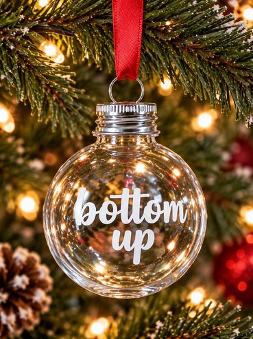 Christmas ornament with "bottom up" text hanging on tree.