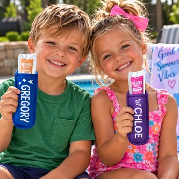 Two kids holding personalized sunscreen pouches by the pool.