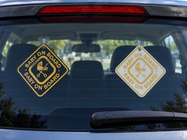Two baby on board signs on a car's rear window.