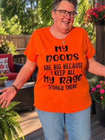 Smiling woman in orange shirt with witty text.