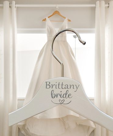 Wedding dress with personalized hanger saying 'Brittany bride.'