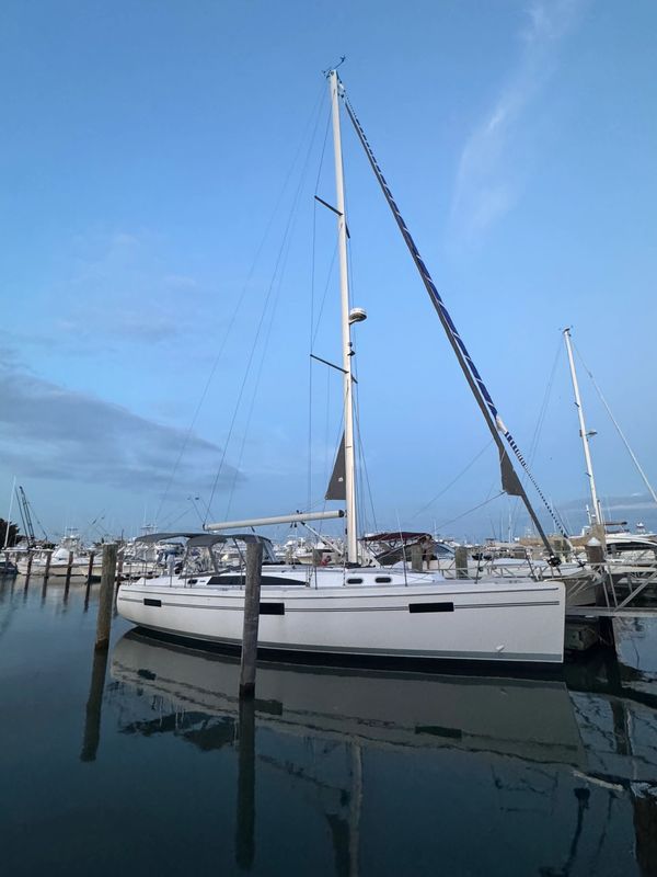 Sailboat docked at calm marina under clear sky.
