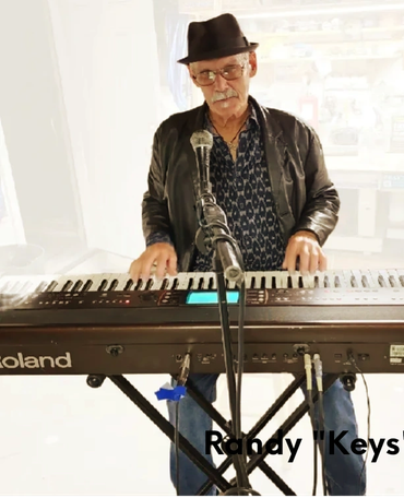 Older man playing keyboard with microphone in front.