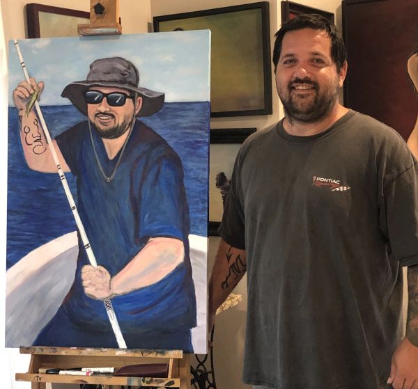 Man standing next to a painting of himself fishing.
