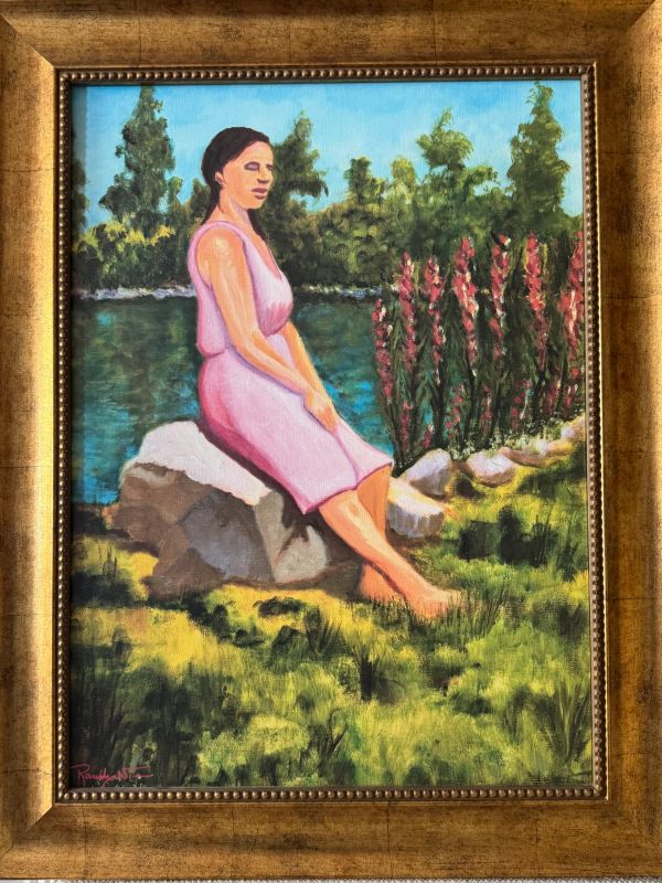 Woman in pink dress sitting on a rock near water.