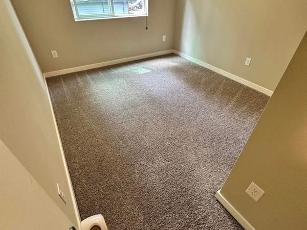 Empty room with beige walls and carpeted floor.
