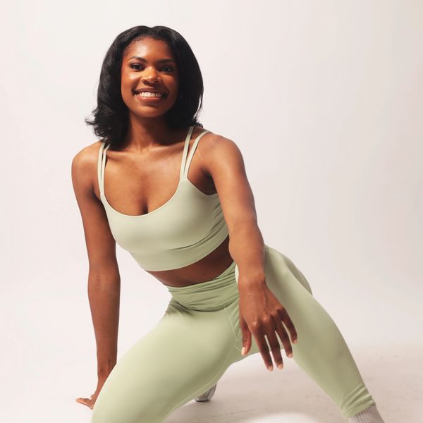 Smiling woman in light green activewear posing.