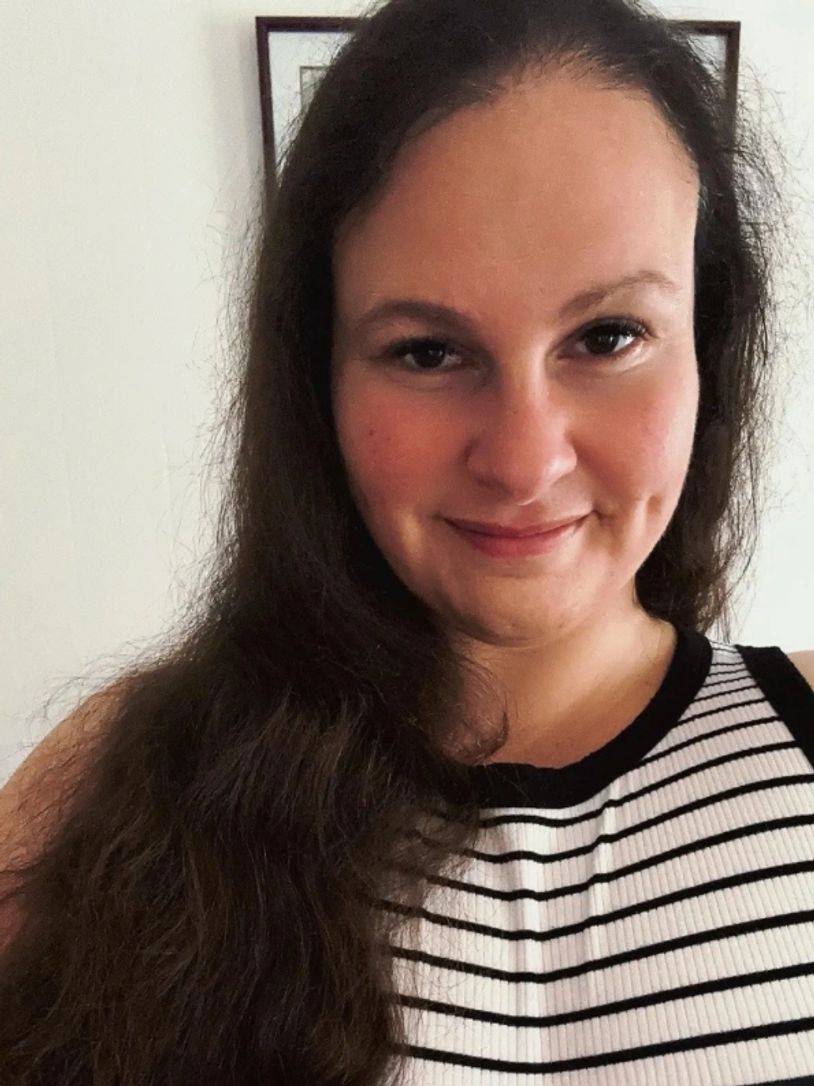 Smiling woman with long brown hair wearing a black and white striped top.