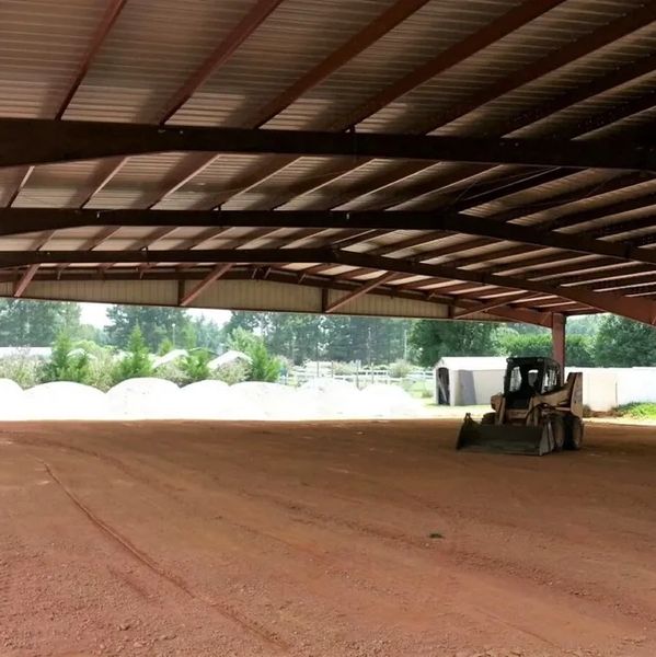 Large covered area with construction vehicle on dirt floor.