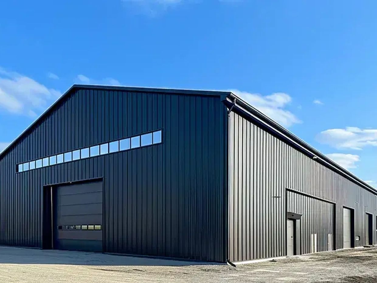 Modern black industrial warehouse under a blue sky.
