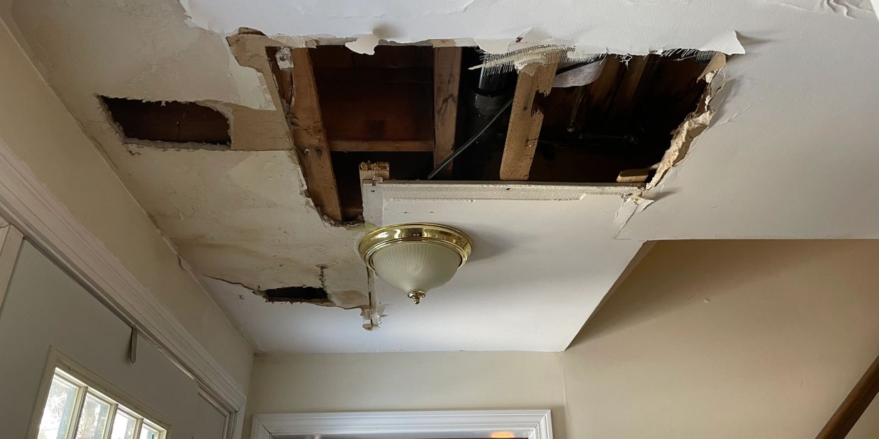 Ceiling with large damaged and exposed wooden beams and plaster.
