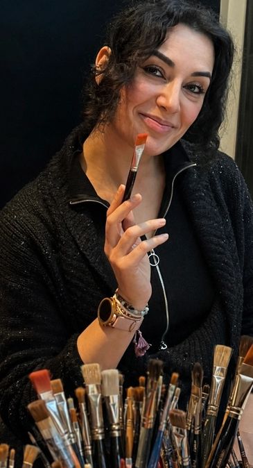 Woman holding a paintbrush with a smile.