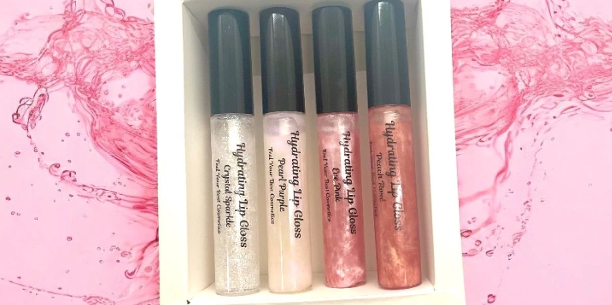 Set of four hydrating lip glosses in a white box on a pink splash background.