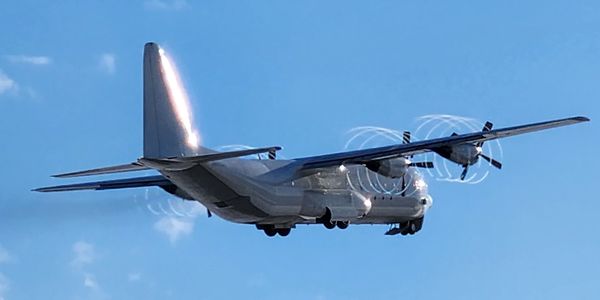 Military transport aircraft flying against a clear blue sky.