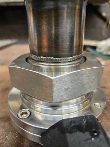 Close-up of a metal pipe with welded joint and hex nut.