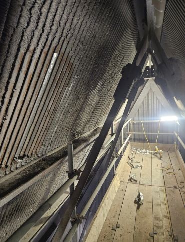 View inside an attic with wooden beams and lighting.