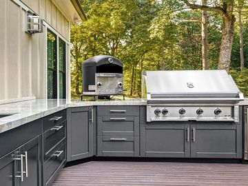 Modern outdoor kitchen with stainless steel grill and pizza oven.