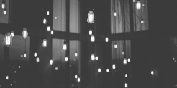 series of almost 50 bare lightbulbs hanging from high ceiling in a dark room slightly blurred