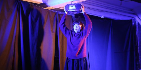 Person holding a boombox above their head in blue and purple lighting.