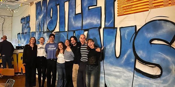 Group of friends smiling together in front of a colorful graffiti wall.