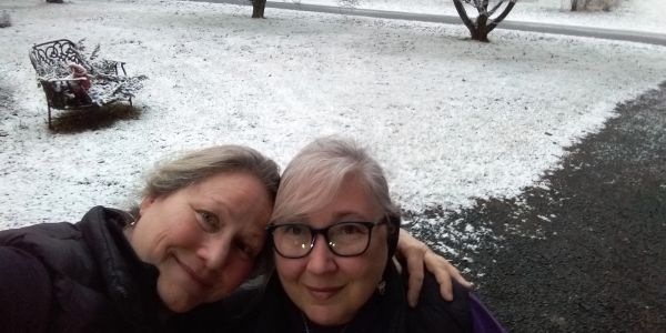 Two women taking a selfie in a snowy outdoor setting.