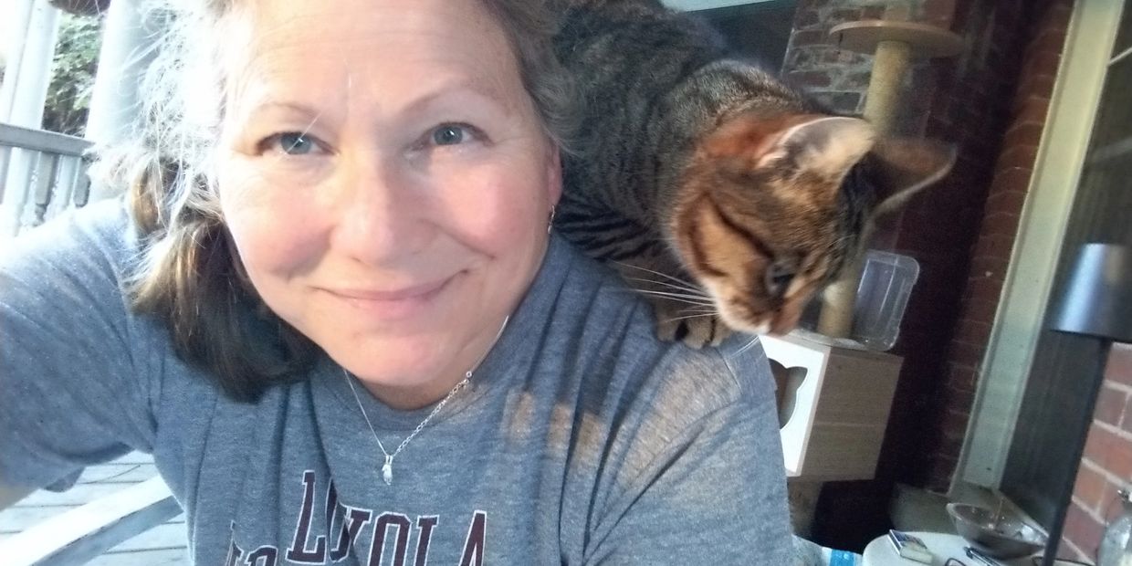 Woman smiling with a cat on her shoulder.