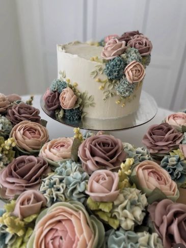 Elegant cake and cupcakes with detailed floral icing in pastel colors.