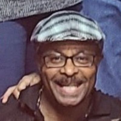 A smiling man wearing glasses and a striped cap.